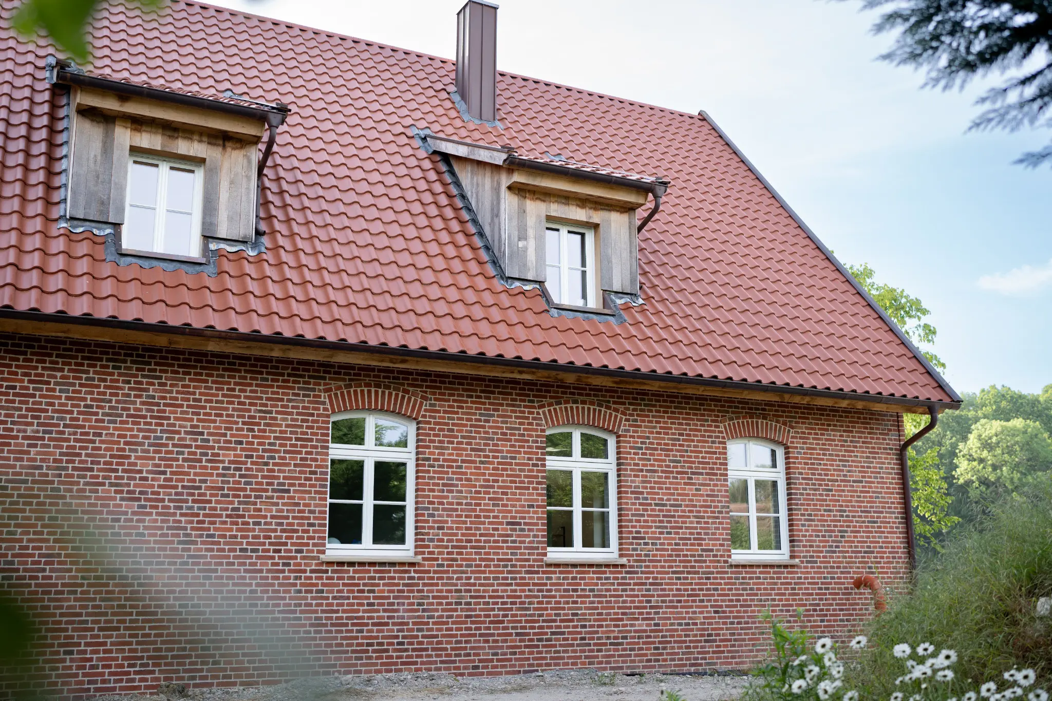 Weiße Holz-Rundbogenfenster im roten Klinkerneubau in Ennigerloh